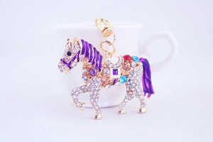 Detailed close-up of a golden horse keychain with sparkling crystals and purple enamel work
