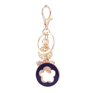 Golden clover keychain with blue enamel, rhinestones and circular tags on white background