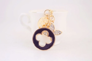 Detail view of gold keychain with black enamel clover and rhinestone love charms