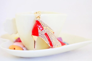 Close-up of a red high heel keychain with sparkling crystals on a golden alloy base