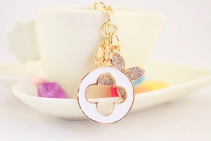 Detail of gold keychain with white enamel four-leaf clover pendant and sparkling crystals