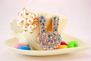 Détail du porte-clés lapin aux strass bleus et perles sur le rebord d'une tasse