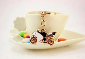 Dettaglio di un portachiavi creativo a forma di moto con strass appeso a una tazza a cuore