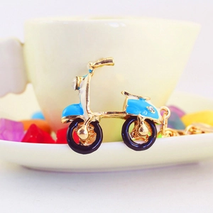 Porte-clés moto scooter bleu orné de strass brillants sur un plat en céramique