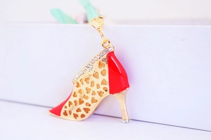 Detail of red high heel pendant with heart cutouts and rhinestones on gold alloy