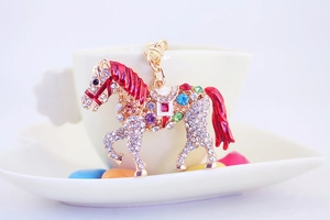 Close-up of golden horse keychain with colorful rhinestones and red enamel mane