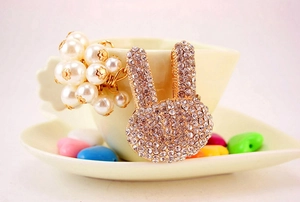 Détail d'un porte-clés lapin doré avec cristaux et perles blanches sur une tasse à café