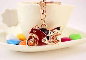 Dettaglio del portachiavi moto rosso e nero con strass appeso a una tazza di porcellana bianca