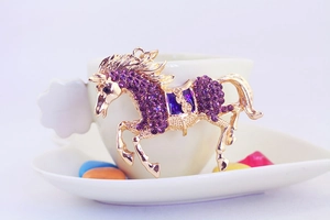 Close-up of golden horse keychain pendant with sparkling purple rhinestones
