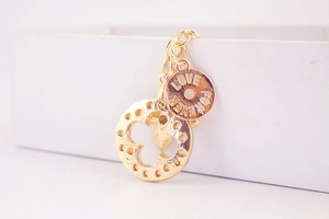 Macro detail of golden clover pendant and Forever Love engraved tag on keychain