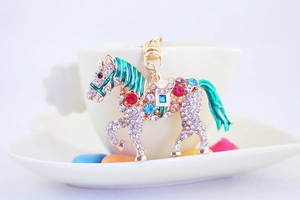 Detailed close-up of a golden horse keychain with colorful rhinestones on a cup edge