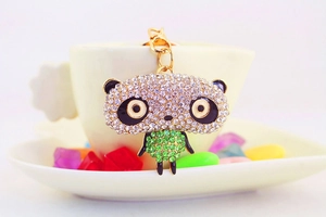 Close-up of golden panda keychain with white and green rhinestones on a ceramic cup
