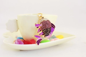 Nahaufnahme eines lila Strass-Karpfen-Schlüsselanhängers an einer weißen Kaffeetasse