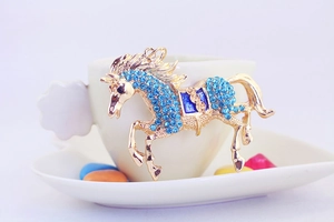Detailed view of horse-shaped golden keychain featuring vibrant blue rhinestones