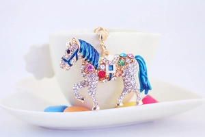 Detail of crystal-encrusted horse keychain hanging on a white ceramic coffee cup