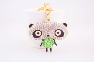Detail of cute panda keychain with white and green rhinestones on gold metal ring