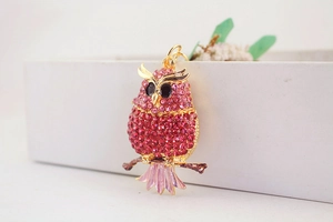 Close-up of owl keychain with sparkling pink rhinestones on a gold branch detail
