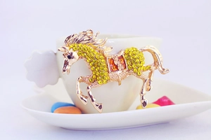 Close-up of a golden horse keychain with yellow rhinestones and red enamel details