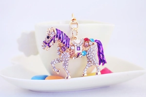 Close-up of a golden horse keychain with sparkling rhinestones and purple enamel mane