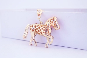 Macro view of gold horse keychain with hollow polka dots and crystal accents