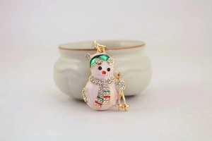 Detail of a Christmas snowman keychain featuring white pearls and green enamel hat