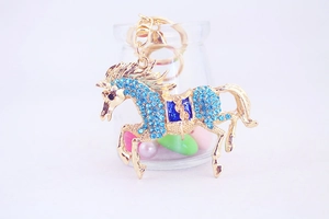 Close-up of golden horse keychain with sparkling blue rhinestones and enamel saddle