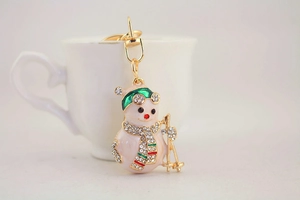 Detailed close-up of a skiing snowman keychain with white rhinestones and green enamel