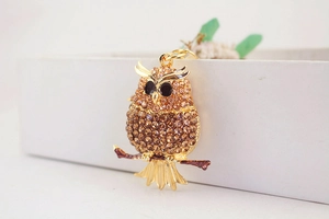 Macro shot of owl keychain detail with amber rhinestones and gold-plated alloy base