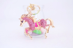 Detail of pink rhinestone flying horse keychain with golden metal and enamel finish
