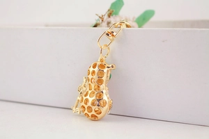 Close-up of golden hollow peanut keychain with a small monkey and green stone detail