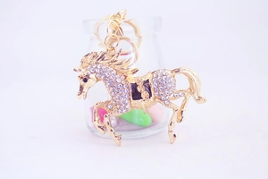 Detailed close-up of a gold-toned horse keychain decorated with sparkling white rhinestones
