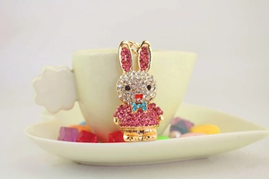 Detailed macro view of a pink rhinestone rabbit keychain on a yellow coffee cup