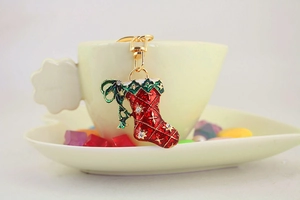 Macro detail of red enamel Christmas stocking keychain with rhinestones on a cup rim