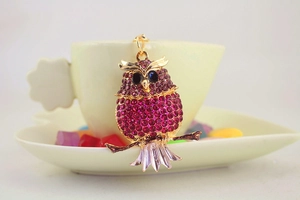 Close-up of owl keychain with rose red rhinestones and blue gem eyes on golden base