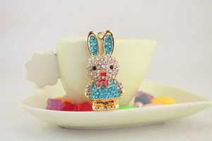 Detail of blue rhinestone bunny keychain hanging on a cup with cute decorative stones