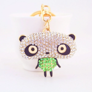 Sparkling rhinestone panda keychain with green crystals and gold ring on ceramic cup