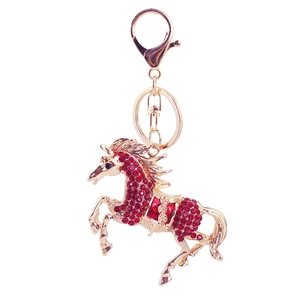Close-up of golden horse keychain with red rhinestones and metallic spring hook