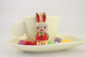 Close-up of cute rabbit keychain with red and white rhinestones hanging on a yellow cup