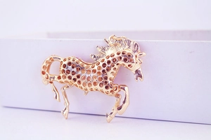 Detail of a golden flying horse keychain with intricate hollow mesh design on a gift box
