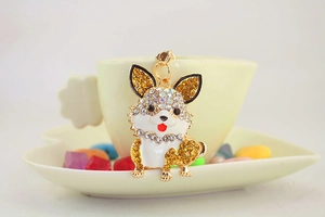 Makro-Detail des strassbesetzten Corgi-Schlüsselanhängers am Tassenrand mit Goldring