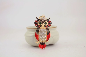 Detailed view of rhinestone owl keychain with green gem eyes and colorful enamel wings