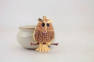 Close-up of owl keychain with champagne rhinestones on a gold branch and black crystal eyes