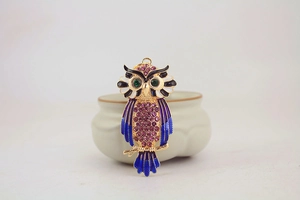 Detailed macro view of colorful rhinestone owl keychain with enamel finish on gold branch