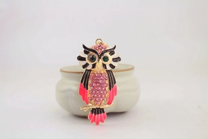 Close-up of owl keychain featuring pink rhinestones and black enamel on gold base