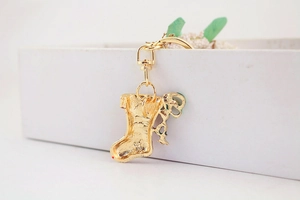 Close-up of the golden metal Christmas stocking keychain with clasp detail in a gift box