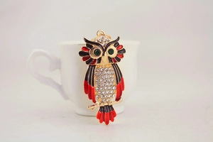 Detailed view of colorful owl keychain with green gemstone eyes and white rhinestones