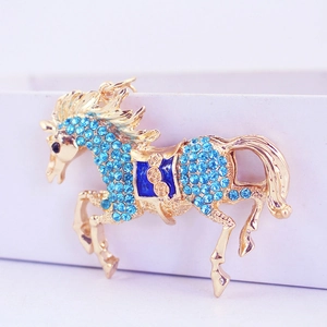 Golden flying horse keychain with blue rhinestones and saddle detail on gift box