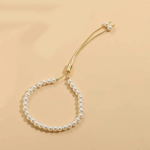Detail of adjustable gold slider clasp and elegant white pearls on a minimalist bracelet
