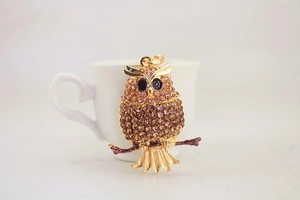 Macro detail of golden owl keychain with sparkling brown crystals and black gem eyes