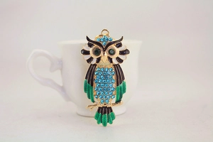 Detailed macro of crystal owl keychain featuring blue rhinestones and green enamel wings